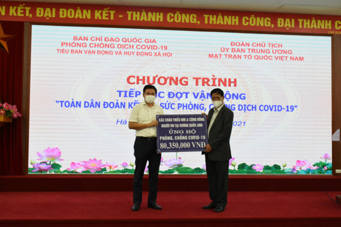 Thứ trưởng Phạm Quang Hiệu thay mặt các cháu thiếu nhi và  cộng đồng người Việt tại Vương quốc Anh trao tiền ủng hộ cho Mặt trận Tổ quốc Việt Nam