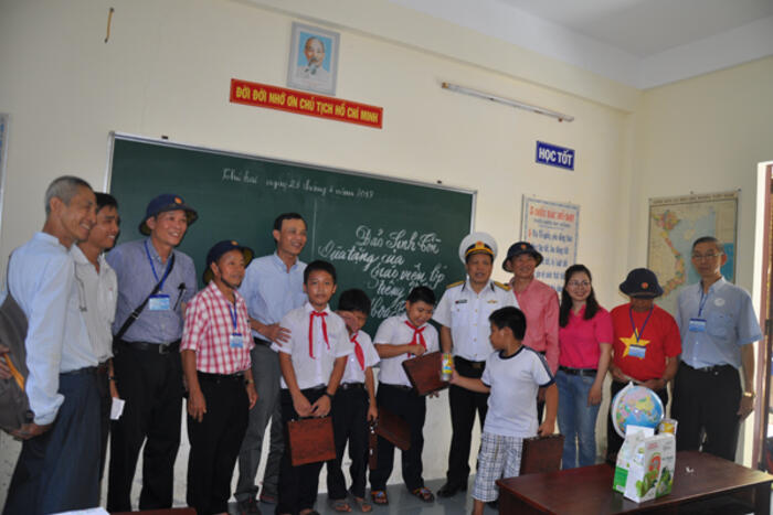 Ông Lương Thanh Nghị, trưởng đoàn cùng với kiều bào tặng quà cho các em học sinh tiểu học