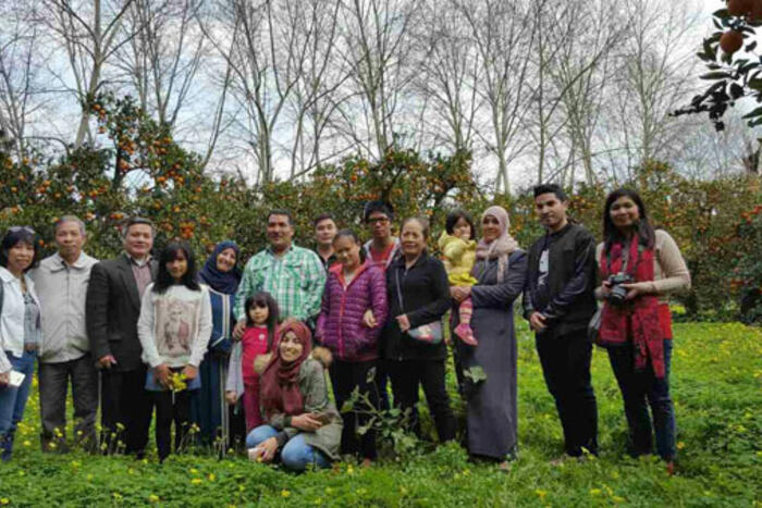 Đoàn công tác chụp ảnh lưu niệm khi tham quan vườn cam, quýt gia đình anh Ali