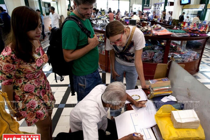 Nhiều du khách nước ngoài tham quan Bưu điện cũng tò mò theo dõi công việc của ông Ngộ