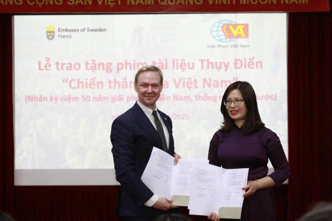 Ông Oscar Staffas Edström - trưởng bộ phận thương mại và xúc tiến Đại sứ quán Thụy Điển tại Việt Nam - trao quyết định tặng phim cho bà Lê Thị Hà - Viện trưởng Viện Phim Việt Nam. (Nguồn: Đại sứ quán Thụy Điển tại Việt Nam) trao-tang-phim.jpg