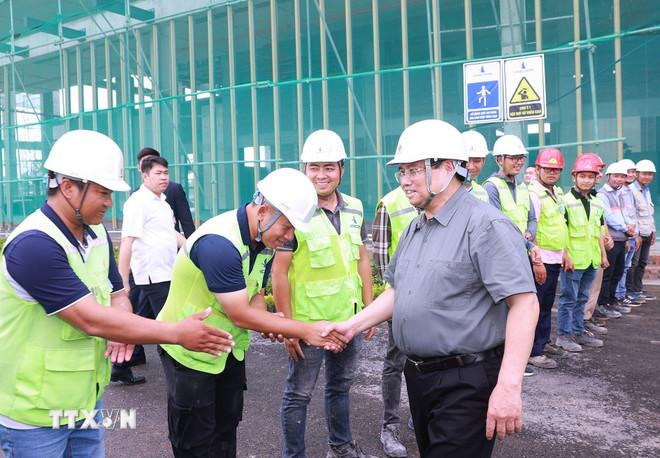 Thủ tướng Phạm Minh Chính với công nhân, kỹ sư thi công dự án Trung tâm Hội chợ Triển lãm Quốc gia tại huyện Đông Anh, Hà Nội. (Ảnh: Dương Giang/TTXVN) ttxvn-1905-thu-tuong-trung-tam-hoi-cho-trien-lam-quoc-gia-7.jpg