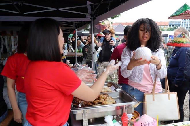 Một du khách địa phương đang hỏi mua sản phẩm dừa nước của tỉnh Bến Tre được bày bán tại quầy hàng của Sứ quán Việt Nam. (Ảnh: Việt Dũng/Vietnam+) du-khach.jpg