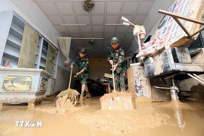Lực lượng quân đội hỗ trợ người dân tổ 4, xã Sông Mã, Sơn La, thu gom bùn đất, cành cây, rác bị tràn về trong đợt lũ vừa qua. (Ảnh: Quang Quyết/TTXVN) ttxvn-mua-lu-son-la-2.jpg