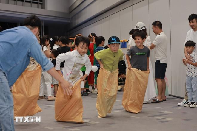 Các em bé Việt Nam tại Sakai hào hứng tham gia trò chơi nhảy bao bố trong đêm hội Trung Thu tại Sakai. (Ảnh: Nguyễn Tuyến/TTXVN) ttxvn-trung-thu-sakai-2.jpg