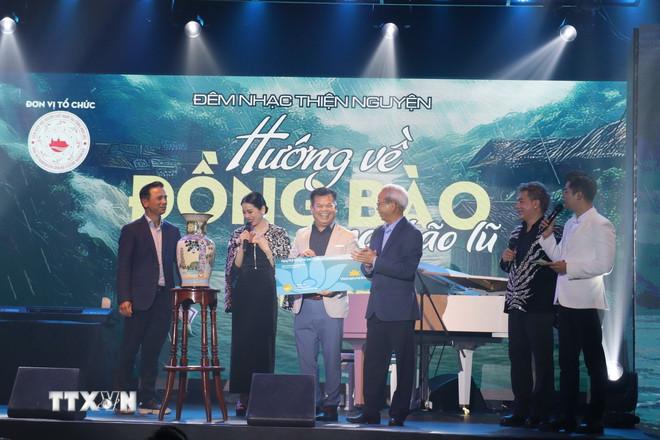 Ca sỹ Lệ Quyên trao sản phẩm đấu giá cho người thắng cuộc đấu giá trong chương trình gây quỹ tại sự kiện. (Ảnh: Việt Dũng/TTXVN) ttxvn-thien-nguyen-2-resize.jpg
