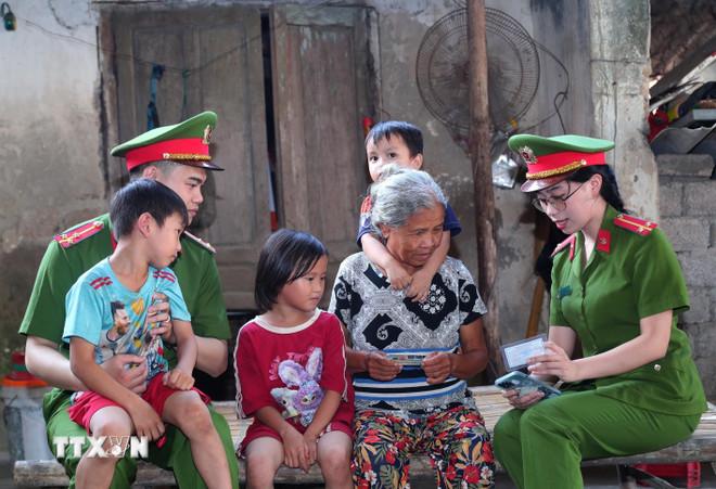 Cán bộ Công an xã đến tận hộ gia đình tuyên truyền, hướng dẫn người dân thực hiện các thủ tục hành chính trên môi trường điện tử, góp phần thực hiện hiệu quả Đề án 06 của Chính phủ. (Ảnh: Trọng Đức/TTXVN) ttxvn-cong-an-nhan-dan-4.jpg